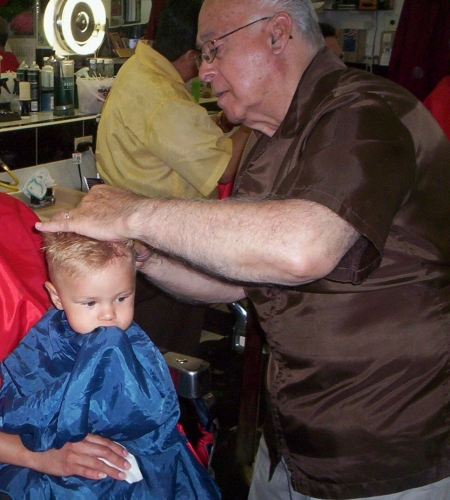 Sammy in barber chair chewing on cape